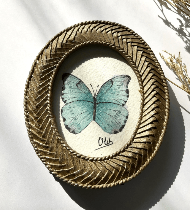 Papillon bleu irisé dans son cadre miniature doré