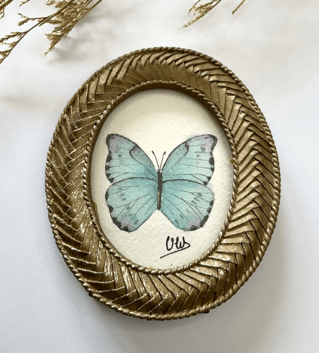 Papillon bleu irisé dans son cadre miniature doré